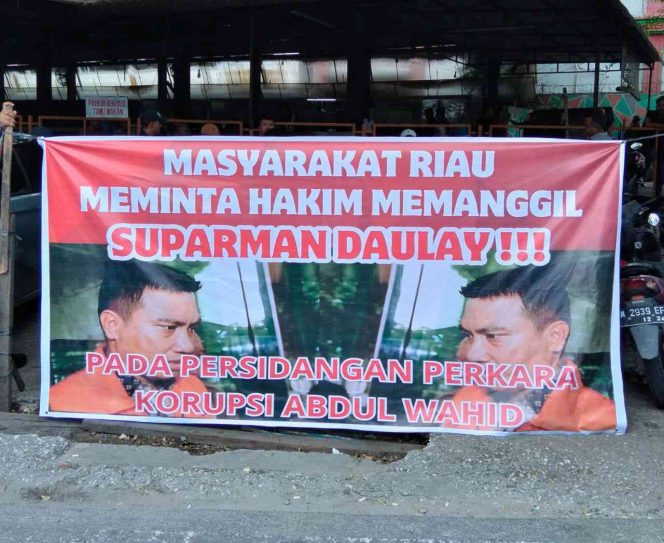
					Desak Suparman Diperiksa Hakim, Masyarakat Riau bentangkan Spanduk didepan PN Pekanbaru.